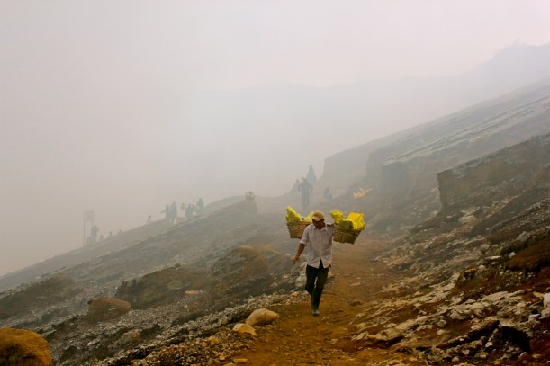A porter emerges from the sulfurous mist on the path from Mount Ijen's crater.