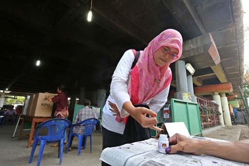 A woman dips her finger in ink after casting her vote during the legislative election at a polling station under the toll road in North Penjaringan, North Jakarta, on Wednesday ( Photo: Jakarta Post)